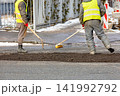 Workers repair a road in a city during daylight hours with tools and equipment 141992792