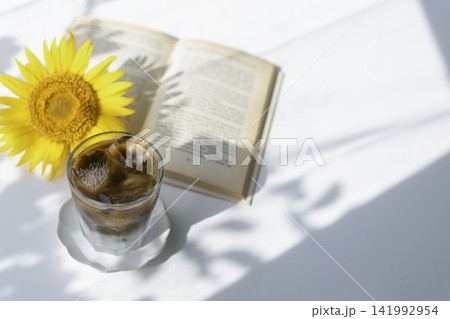 ひまわりと読書を楽しむ夏のアイスコーヒー ひまわりと読書を楽しむ夏のアイスコーヒー 141992954