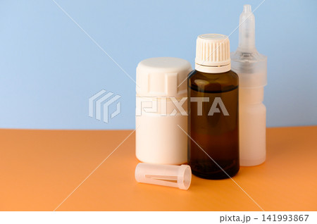 Elegant bottles arranged on a vibrant orange surface beside a soft blue background create a soothing and minimalist atmosphere Elegant bottles arranged on a vibrant orange surface beside a soft blue background create a soothing and minimalist atmosphere 141993867