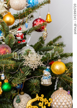 A Christmas tree stands with many colorful ornaments hanging from its branches. Each ornament shows different shapes and colors, celebrating the festive season and bringing joy to the home A Christmas tree stands with many colorful ornaments hanging from its branches. Each ornament shows different shapes and colors, celebrating the festive season and bringing joy to the home 141994720