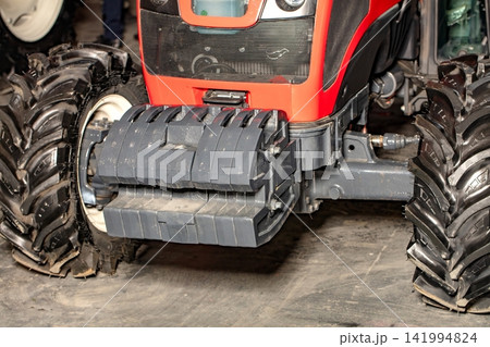 Tractor with large wheels and front attachment for farming work in a barn 141994824