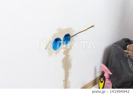 Apartment wall preparation for electrical outlets includes blue conduit boxes and exposed colored wires Apartment wall preparation for electrical outlets includes blue conduit boxes and exposed colored wires 141994942