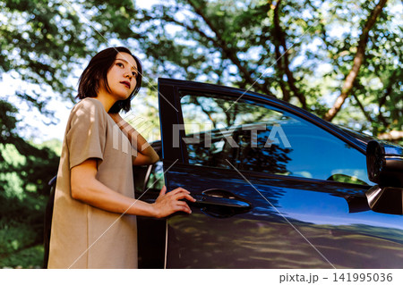 車に寄りかかる女性、木漏れ日 車に寄りかかる女性、木漏れ日 141995036