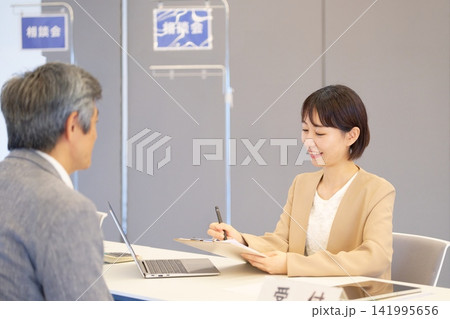 相談会の受付で来場者に応対する女性スタッフ 相談会の受付で来場者に応対する女性スタッフ 141995656