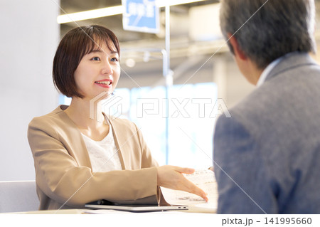 笑顔で相談に応対する女性担当者とシニア男性 笑顔で相談に応対する女性担当者とシニア男性 141995660