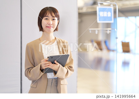 タブレットを持って笑顔を見せる若い女性相談員 141995664
