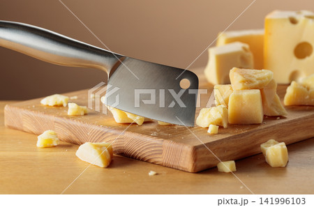 Parmesan cheese and knife on a cutting board. 141996103