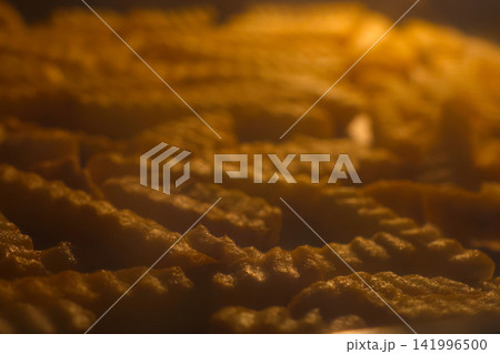 Golden Crinkle-Cut French Fries Baking in Oven - Perfect for Food and Snack Advertisements 141996500