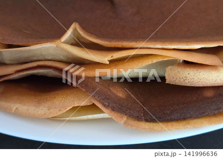 Close-Up of Golden Crepes Layers on White Plate for Culinary Design and Food Blog Close-Up of Golden Crepes Layers on White Plate for Culinary Design and Food Blog 141996636