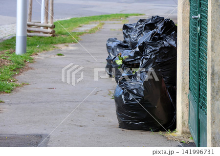 Urban Cleanup: Pile of Garbage Bags on City Sidewalk for Waste Management Awareness Urban Cleanup: Pile of Garbage Bags on City Sidewalk for Waste Management Awareness 141996731