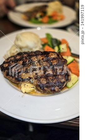 Grilled Ribeye Steak with Herb Butter, Mashed Potatoes and Roasted Vegetables on Plate Grilled Ribeye Steak with Herb Butter, Mashed Potatoes and Roasted Vegetables on Plate 141997119