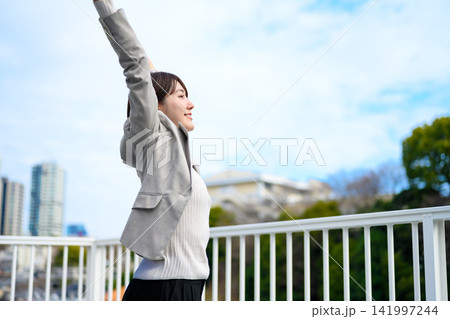 バルコニーで大きく背伸びをしてリフレッシュする女性 バルコニーで大きく背伸びをしてリフレッシュする女性 141997244