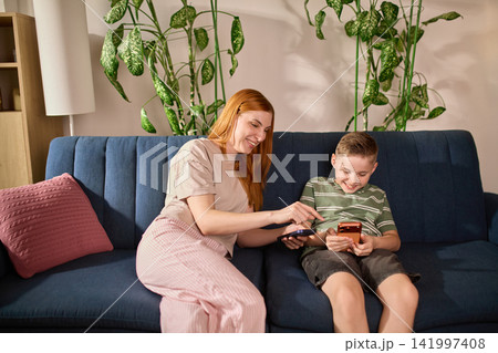 Mother and son discussing digital spending on smartphones Mother and son discussing digital spending on smartphones 141997408