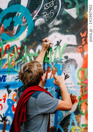 Visitor writing on the John Lennon Wall in Prague 141997462