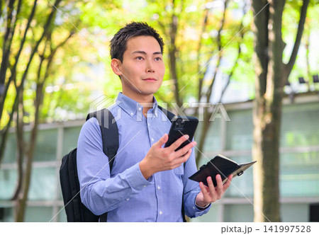 スマートフォンと手帳を持つ男性 141997528