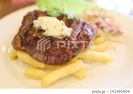 Grilled Steak with Herb Butter and French Fries Close-up Grilled Steak with Herb Butter and French Fries Close-up 141997604