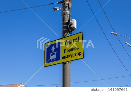Yellow tow truck warning road sign mounted on a utility pole against a clear blue sky, illustrating strict traffic enforcement, public parking compliance, and urban safety regulations Yellow tow truck warning road sign mounted on a utility pole against a clear blue sky, illustrating strict traffic enforcement, public parking compliance, and urban safety regulations 141997661