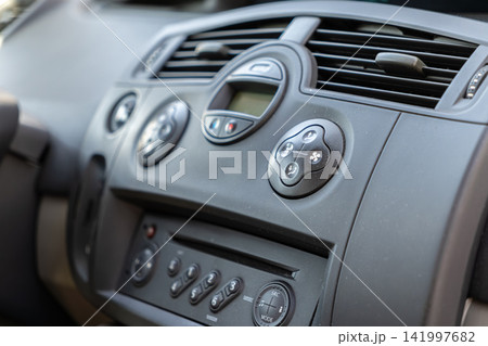 Modern vehicle interior dashboard with climate control buttons and digital media center display panel illustrating automated car comfort features for driver and passenger travel 141997682