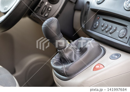 A manual gear shift lever in a modern car interior features a black leather knob and console controls to represent the driving experience and mechanical control in a daily commute A manual gear shift lever in a modern car interior features a black leather knob and console controls to represent the driving experience and mechanical control in a daily commute 141997684