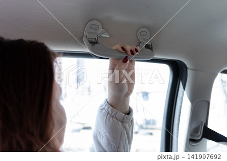 A passenger firmly grips the overhead assist handle inside a moving vehicle to emphasize safety and stability during daily commutes while traveling across busy urban city streets 141997692