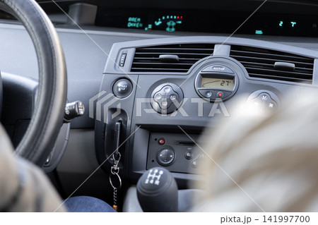 Modern vehicle interior dashboard showing the steering wheel gear stick and climate controls during a road journey to represent safe transportation and premium automotive travel 141997700