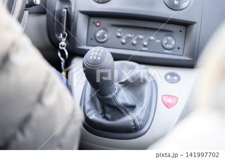 A manual gear stick inside a modern car dashboard with a focus on the shift lever showing five speed gears and reverse, representing the pure experience of driving control A manual gear stick inside a modern car dashboard with a focus on the shift lever showing five speed gears and reverse, representing the pure experience of driving control 141997702