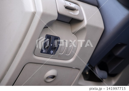 A headlight beam height adjustment dial and interior lighting control switches on a modern car dashboard, showcasing essential driver vehicle operation tools in a sleek setup A headlight beam height adjustment dial and interior lighting control switches on a modern car dashboard, showcasing essential driver vehicle operation tools in a sleek setup 141997715