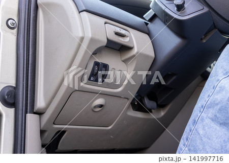 Headlight adjustment controls inside a vehicle cabin, highlighting the dashboard panels near the steering wheel for automotive maintenance, driver comfort, and modern interior tech Headlight adjustment controls inside a vehicle cabin, highlighting the dashboard panels near the steering wheel for automotive maintenance, driver comfort, and modern interior tech 141997716