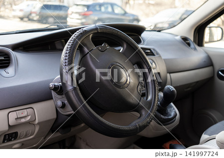 Black leather steering wheel cover inside a modern car cabin, highlighting the interior details of a vehicle while focusing on automotive comfort and aesthetic driving ergonomics Black leather steering wheel cover inside a modern car cabin, highlighting the interior details of a vehicle while focusing on automotive comfort and aesthetic driving ergonomics 141997724