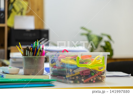 Clear plastic box filled with various colorful stationery items and pencils in a desk organizer, providing a creative and organized atmosphere in a bright modern educational workspace Clear plastic box filled with various colorful stationery items and pencils in a desk organizer, providing a creative and organized atmosphere in a bright modern educational workspace 141997880