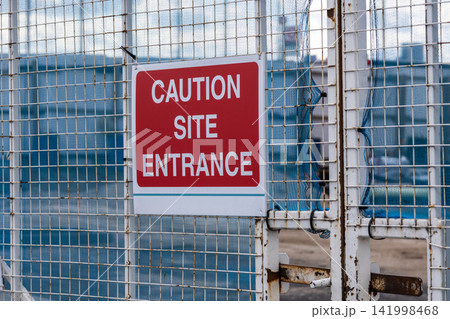Caution site entrance warning sign on perimeter fence Caution site entrance warning sign on perimeter fence 141998468