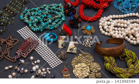 Vintage bohemian jewelry, featuring turquoise beads, pearl necklaces, coral pieces, silver rings, on black background Vintage bohemian jewelry, featuring turquoise beads, pearl necklaces, coral pieces, silver rings, on black background 141998594