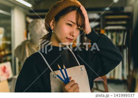 鉛筆を持って考え込む美術学生の女性 鉛筆を持って考え込む美術学生の女性 141999337