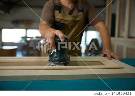 Finishing specialist sanding cabinet door surface 141999421