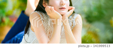 床にうつ伏せの女性、顔に手を添える 床にうつ伏せの女性、顔に手を添える 141999513