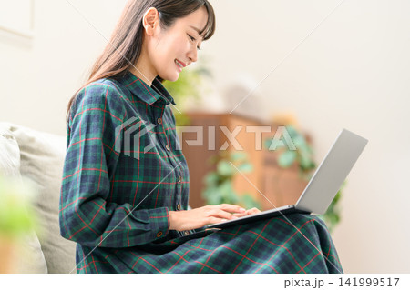 チェック柄ワンピースでノートPCを操作する女性 141999517