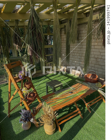 Reeds and cattails are gathered and suspended for drying inside garden house floristry studio. Reeds and cattails hang beside dried plants and floral materials in rustic garden house Reeds and cattails are gathered and suspended for drying inside garden house floristry studio. Reeds and cattails hang beside dried plants and floral materials in rustic garden house 141999741