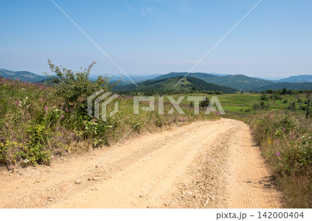 Dusty country road through green hills Dusty country road through green hills 142000404