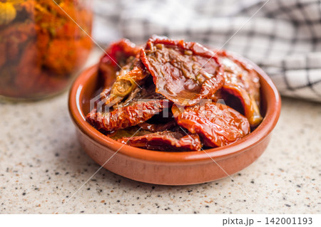 Sun-Dried Tomatoes in Olive Oil in Ceramic Bowl with Jar and Checkered Cloth Sun-Dried Tomatoes in Olive Oil in Ceramic Bowl with Jar and Checkered Cloth 142001193