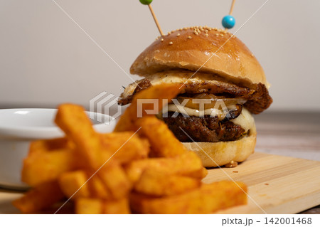 Gourmet Cheeseburger with Fried Egg and French Fries on Wooden Board Gourmet Cheeseburger with Fried Egg and French Fries on Wooden Board 142001468