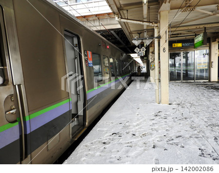 雪の積もる駅のホームに停車する電車とホームの風景 142002086