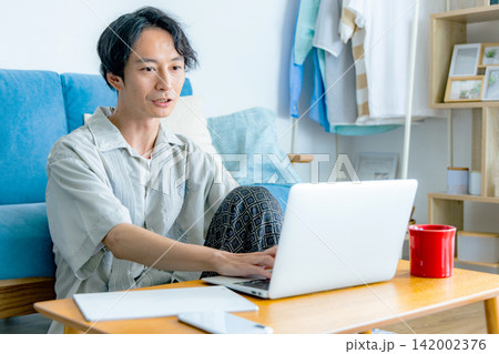 リビングでコーヒーを飲みながら考え事をする男性 リビングでコーヒーを飲みながら考え事をする男性 142002376