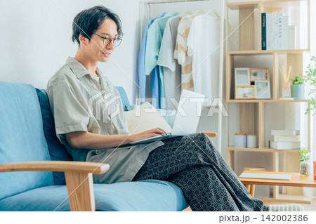 ソファに座ってテレワークをする男性 ソファに座ってテレワークをする男性 142002386