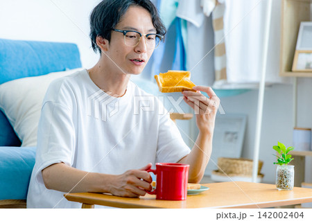 朝ごはんのトーストを食べる若い男性 朝ごはんのトーストを食べる若い男性 142002404