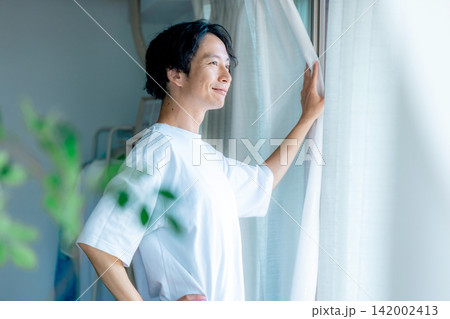 カーテンを開ける男性 142002413
