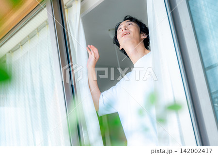 窓の外を眺める若い男性 窓の外を眺める若い男性 142002417