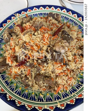 Traditional rice dish featuring beef, carrots, and spices, beautifully arranged on a decorative plate with colorful patterns and designs 142003687