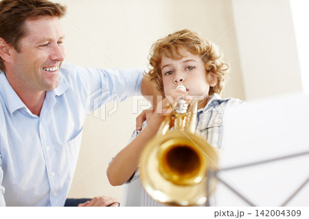 Playing, music sheet and father and child with trumpet for practice, lesson and skills for talent show. Family, creative hobby and dad with young boy with instrument, paper and notes for song at home Playing, music sheet and father and child with trumpet for practice, lesson and skills for talent show. Family, creative hobby and dad with young boy with instrument, paper and notes for song at home 142004309