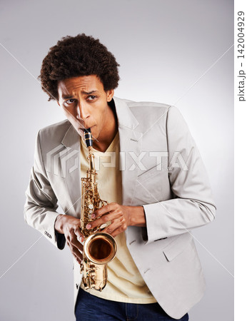 Happy, african man and music, playing the saxophone with casual outfit and clothing in studio. Confident musician, jazz and instrument with trendy suit for band performance on white background Happy, african man and music, playing the saxophone with casual outfit and clothing in studio. Confident musician, jazz and instrument with trendy suit for band performance on white background 142004929