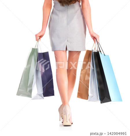 Fashion, shopping bags and legs of woman with presents in studio for deal, sale or discount for luxury. Paper packet, gifts and closeup of female person feet with heels isolated by white background. 142004991